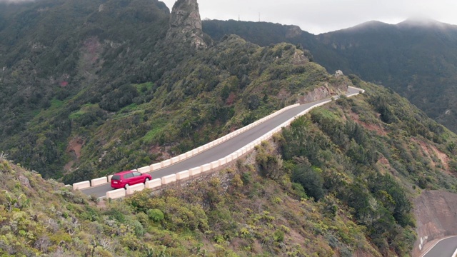 空中风景-一辆孤独的汽车通过一个狭窄和危险的道路在绿色的高山。特内里费岛阿纳加国家公园，高海拔的蛇形山脉视频素材