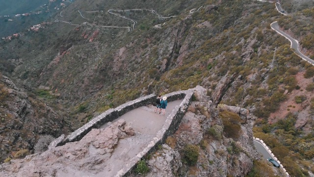 天线。一男一女站在高山上的观景台的边缘。阴天，山谷全景。视频素材