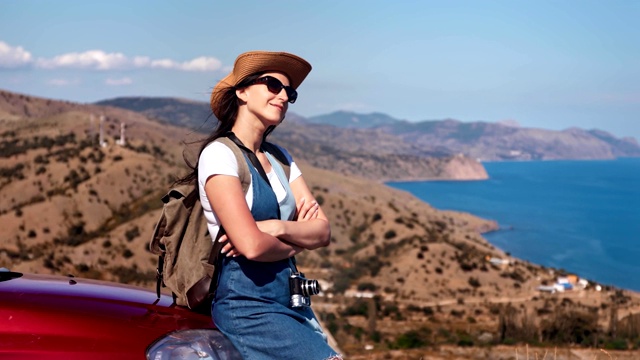 快乐轻松的年轻旅行女人享受日光浴在汽车引擎盖天空在背景视频素材