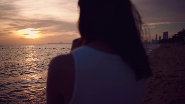 年轻女子在海滩上拍摄日落照片视频素材