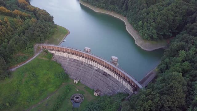 日落时在人工湖上空低空飞行，末端有一座水坝视频素材