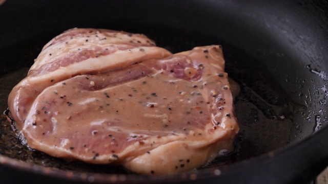 特写在热锅里烤猪肉牛排视频素材