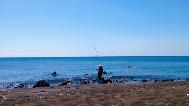 在一个阳光明媚的日子里，两个渔民在村里的热带钓鱼海滩上钓鱼视频素材