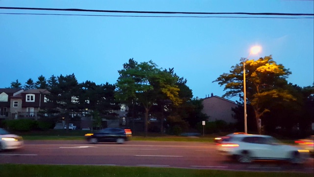 城市道路交通在夜间行驶的侧视图。城市生活与黄昏街灯的城市景观。视频素材