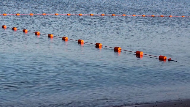 海洋背景。风平浪静的海面上，有一道红色的防护栅栏。选择焦点。关闭，侧视图，复制空间。视频下载