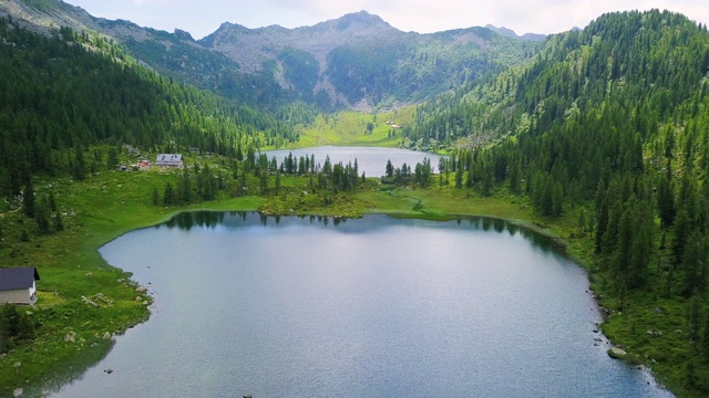 一个湖泊被树木和山脉包围的自然的航空图像。视频素材