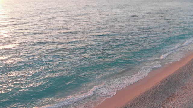 在日落的海滩上海浪打破海岸的鸟瞰图视频素材