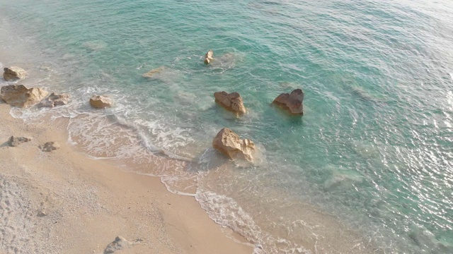 日落时海浪拍打着沙滩上的岩石视频素材