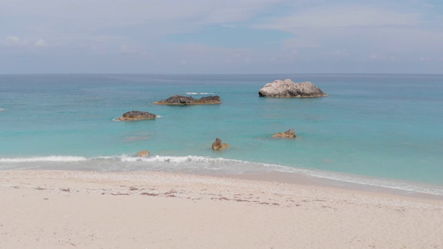 鸟瞰图的沙滩与岩石湾和海浪冲击他们在白天视频素材