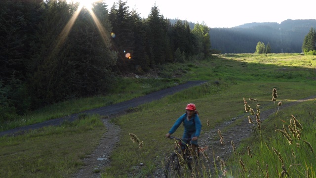 骑山地车的人沿着草甸斜坡下山视频素材