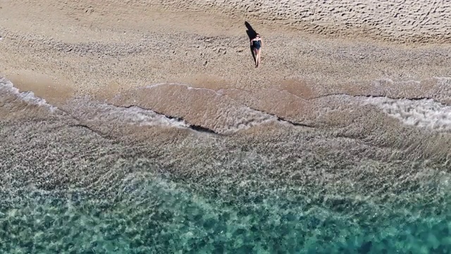 在希腊岛屿上，一名女子在绿油油的海滩上用无人机自拍。视频素材