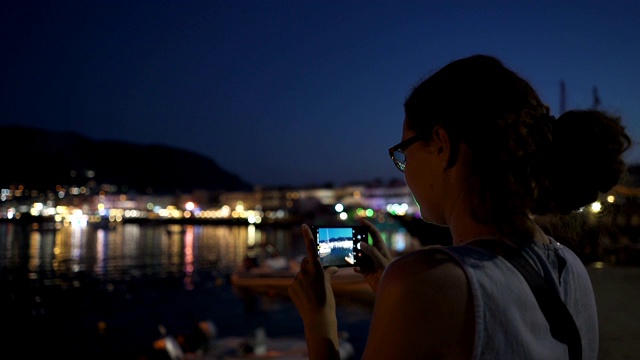 一个年轻的女人通过电话拍摄克里特岛的夜晚海岸视频素材