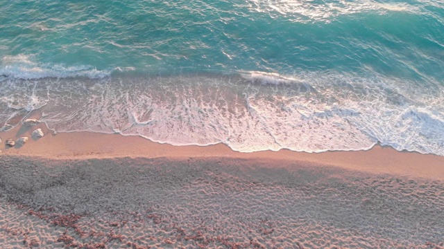 鸟瞰图的海浪翻滚的海岸线在日落，夏天的背景视频素材