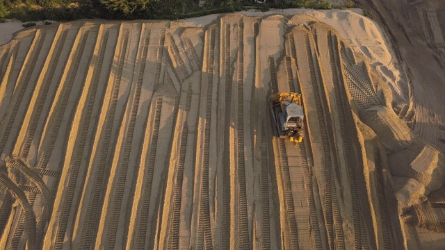 推土机的痕迹。关闭了。施工现场在道路施工现场。夏季傍晚日落时，推土机将沙子和泥土铲开。鸟瞰图视频素材