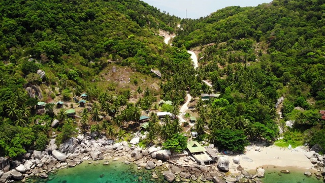 热带火山岛附近海面平静。在泰国阳光明媚的日子里，无人机在石岸附近的蓝色海洋和火山岛的绿色丛林宁静的水。视频素材