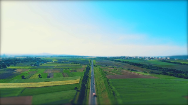 空中模糊的不同类型的汽车沿着空旷的砾石路通过绿色的草地和农田景观。4 k。视频素材