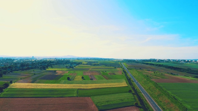 空中飞过田野间的道路，画面一开始就有彩虹砖，蓝色的天空充满了光和温暖。4 k。视频素材