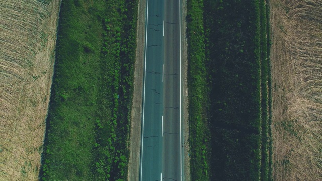 空中模糊的不同类型的汽车沿着空旷的砾石路通过绿色的草地和农田景观。4 k。视频素材