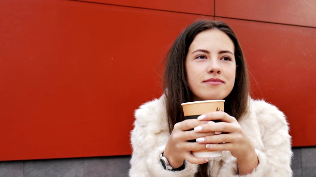 这个女孩在街上的一家咖啡馆里喝咖啡。视频素材