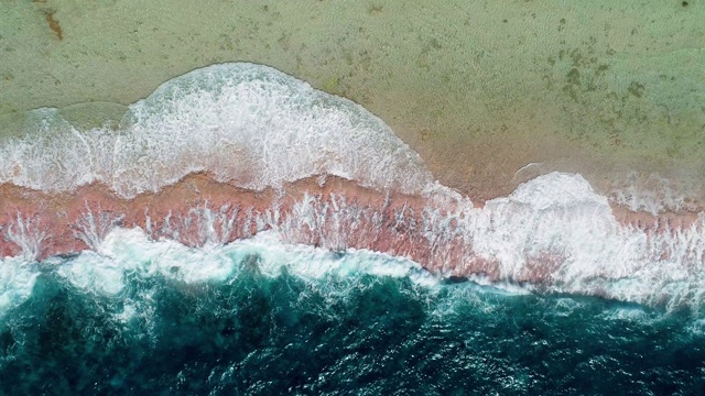 海浪撞击着热带海滩上的珊瑚礁。一半是蓝色的海浪，一半是太平洋的海滩和珊瑚。海浪很大。旅行热带概念-鸟瞰无人机- 4K视频素材