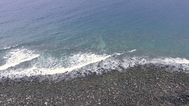 鸟瞰图的石头和鹅卵石在海滩上沐浴在海浪视频素材