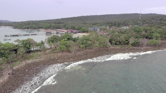 无人机的石头和鹅卵石在海滩上沐浴在海浪。小渔村为背景视频素材