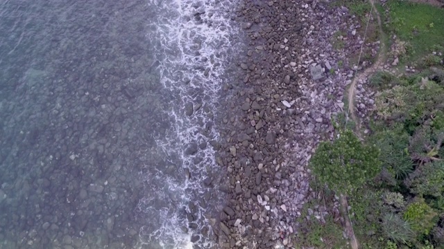 在被海浪淹没的海滩上，飞过石头和卵石视频素材