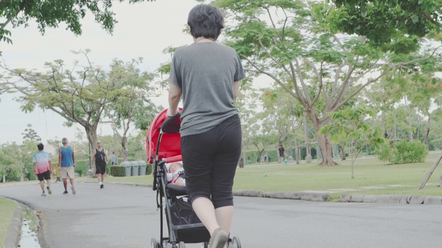 婴儿;母亲走着，推着婴儿车里的男孩视频素材