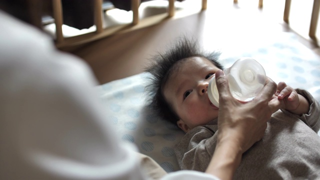 年轻的母亲用奶瓶喂新生儿视频素材