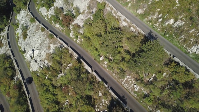 弯弯曲曲的山道边有悬崖峭壁，鸟瞰高山。股票。鸟瞰图景观，蜿蜒的山路在夏季阳光明媚的日子背景视频素材