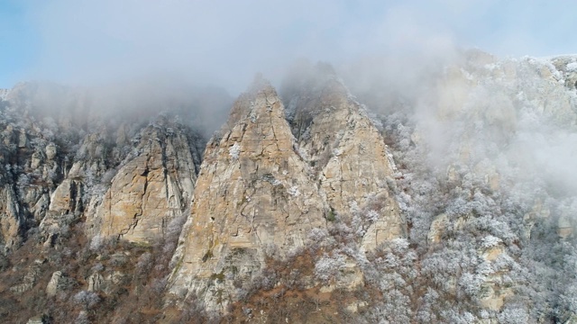 冬季景观与雪山悬崖覆盖冻结的针叶树和灌木在灰色的云对蓝色的天空。射杀。美丽的景色视频素材