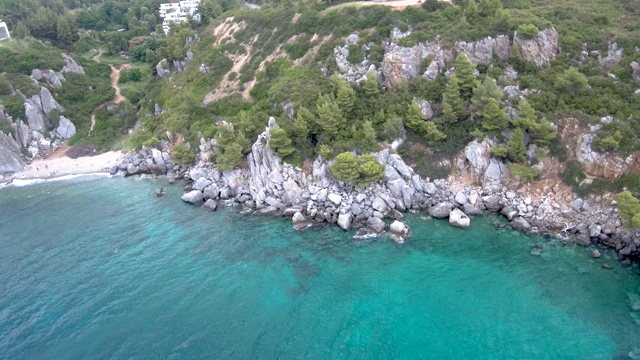 鸟瞰图的小海滩与绿松石水旁边的岩石和树木在Agia Paraskevi Halkidiki地区，希腊视频素材