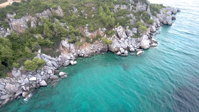 鸟瞰图陡峭的岩石在绿松石水晶海在阿吉亚帕拉斯凯维哈尔基迪基地区，希腊，圆形运动的无人机视频素材