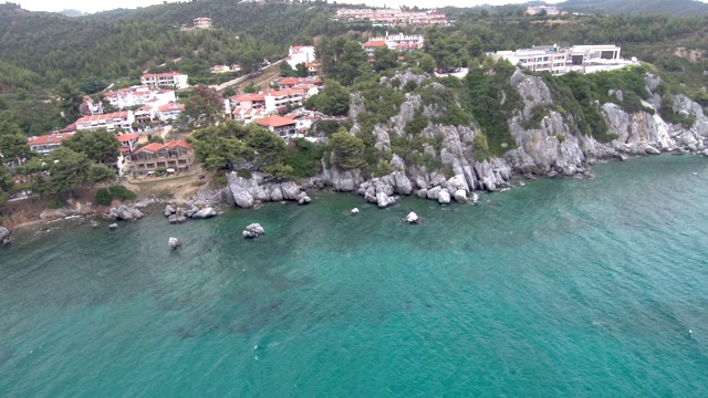 在希腊哈尔基迪基的Agia Paraskevi地区的旅游村庄和温泉设施下面的绿松石海岸的鸟瞰图，由无人机侧移视频素材