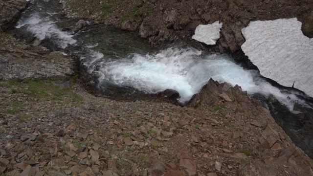 高山景观-顶视图瀑布的高山河流之间流动的石头和雪原视频素材