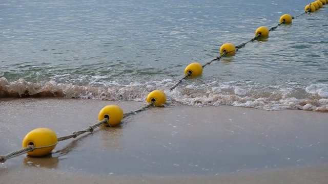 在海滩上，海浪抵岸时漂浮在海上的黄色浮标视频下载