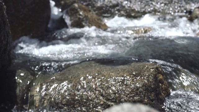 男人的脚踩在流水中的石头上。男脚在鞋走在岩石山河流的旅程。旅游、徒步旅行和旅游视频素材