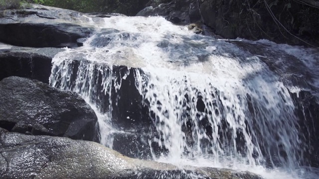 山河中的水流倾泻在巨石上。山上瀑布的水迅速地流入岩石河中。山间湍急的小溪视频素材