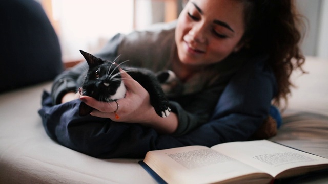 美丽的年轻女子和她的猫在床上视频素材