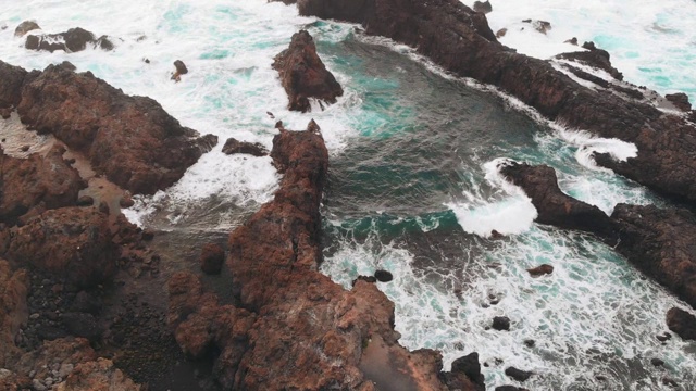 美丽的海湾由冰冻的熔岩峭壁形成，有火山沙的海滩和大西洋。鸟瞰图一个天然的游泳池视频素材