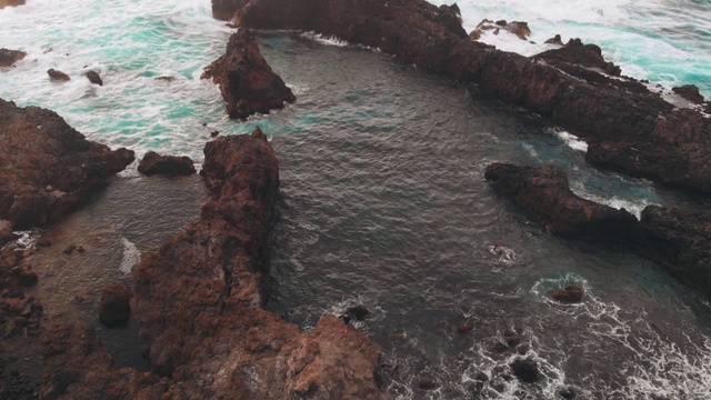 站在世界边缘的人。火山起源的海岸，海洋中的岩石，无人机拍摄的照片。视频素材