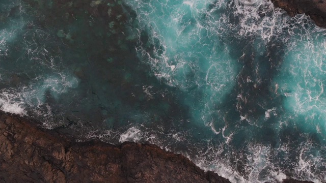 水中的巨石，从冰冻的熔岩中升起。鸟瞰图，清澈的海洋和泡沫特内里费海岸。从无人机视频素材