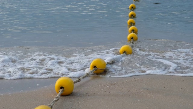 在海滩上，海浪抵岸时漂浮在海上的黄色浮标视频下载