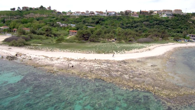 鸟瞰图绿松石海滩下的一个旅游村庄，阿托斯哈尔基迪基希腊，向前移动的无人机视频素材