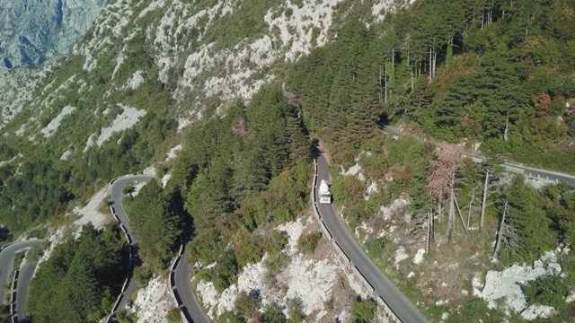 弯弯曲曲的山道边有悬崖峭壁，鸟瞰高山。股票。鸟瞰图景观，蜿蜒的山路在夏季阳光明媚的日子背景视频素材