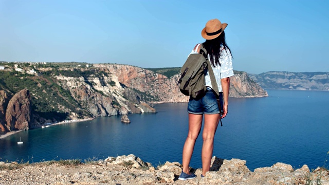 后视图成功的背包旅行者旅行女人钦佩惊人的海的风景被山包围视频素材