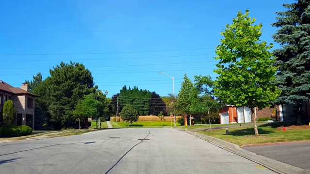 夏季，在绿树成荫的住宅城市道路上驾驶接近停车标志。司机视角:沿着美丽的阳光郊区街道慢过停车标志。视频素材