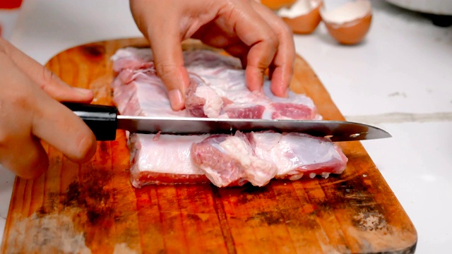 在厨房的砧板上，妇女们用刀将猪肉切成小块视频素材