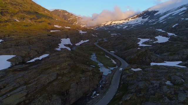 航拍:挪威达尔斯尼巴山高原冬季在岩石中间的山路上行驶的房车视频素材