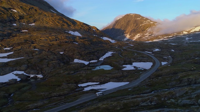 航拍:挪威达尔斯尼巴山高原，露营车在冬天被雪覆盖的岩石中行驶视频素材